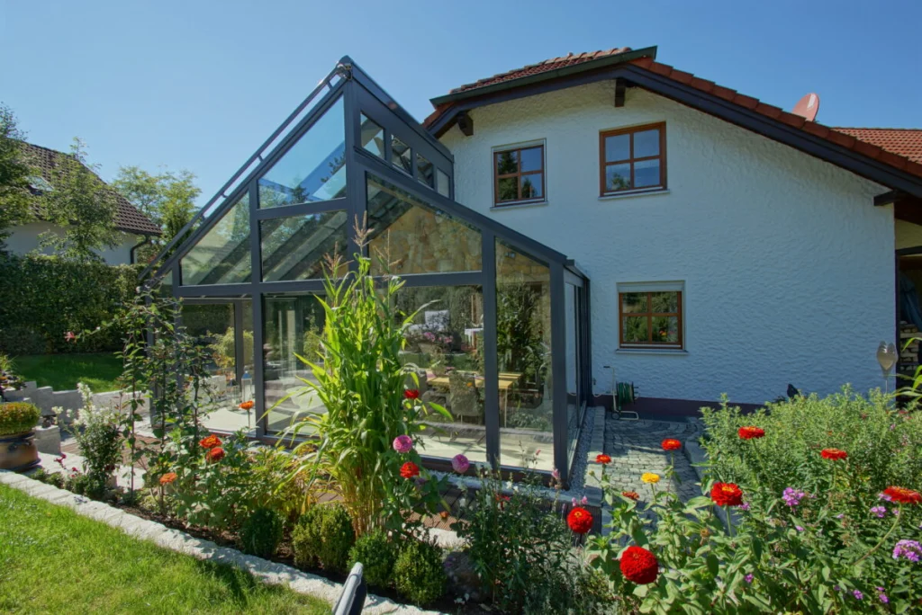 Wintergarten in Bayreuth von außen, Glasanbau mit Satteldach und anthrazitfarbenen Profilen an einem weißen Haus