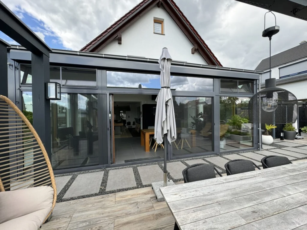 Anbau in Benzendorf mit Flachdach, anthrazitfarbener Außenschale und Schiebetür, von der Terrasse gesehen