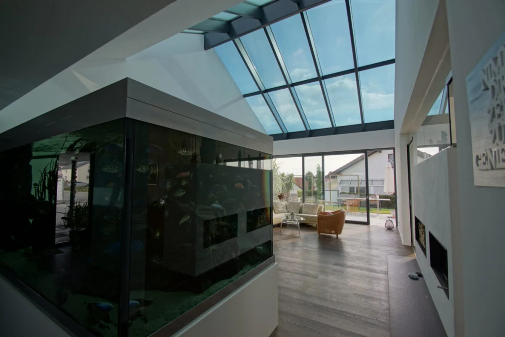 Wohnraum in Buckenreuth mit Glasdach, großem Aquarium, Schiebetür zur Terrasse und Sofa