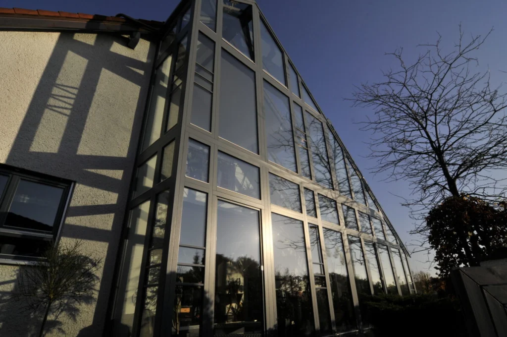 Verglaste Giebelseite des Hauses in Fürth mit anthrazitfarbenen Rahmen über drei Geschosse, von unten gesehen
