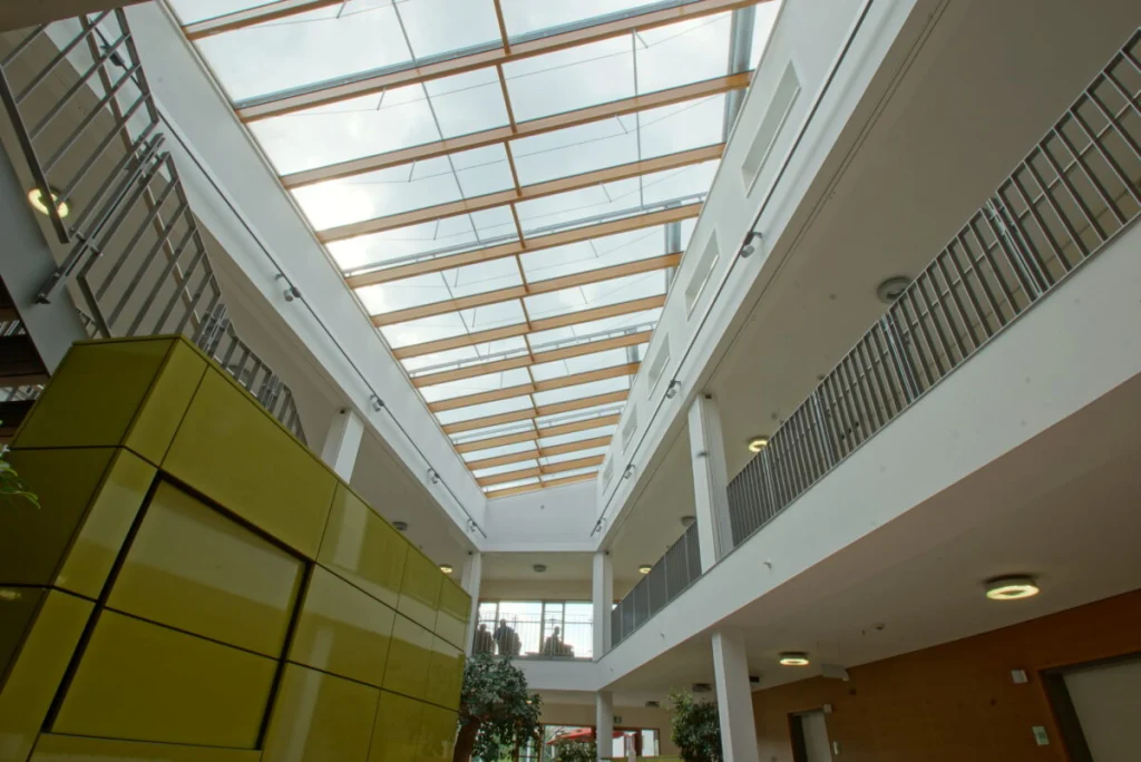 Glasdach über dem Atrium der Klinik Ebermannstadt von unten, Holzsparren und Beschattung, umlaufende Galerie