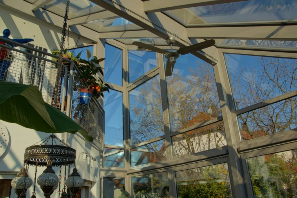 Glasdach des Wintergartens in Möhrendorf von unten mit Deckenventilator, Galerie mit Gittergeländer und Mosaikleuchte