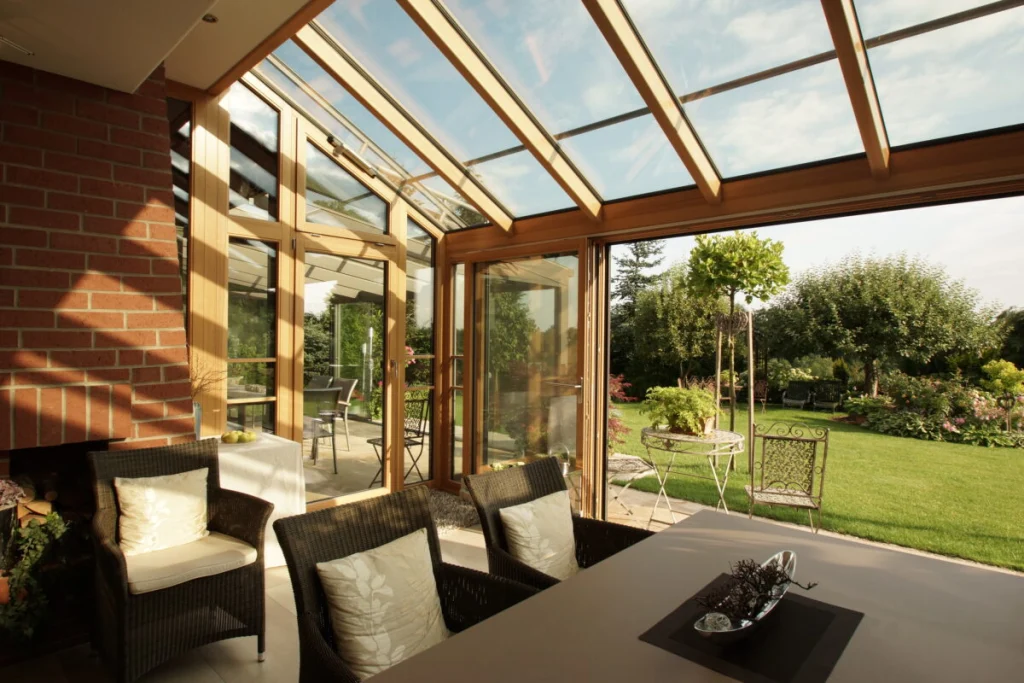Wintergarten in Oberalbach mit Holzkonstruktion aus Meranti natur, Pultdach aus Glas und offener Schiebetür zum Garten