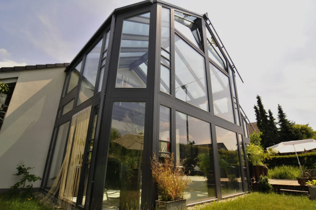 Wintergarten in Baiersdorf aus niedriger Perspektive, Ecke der zweigeschossigen Glaskonstruktion mit anthrazitfarbenen Rahmen
