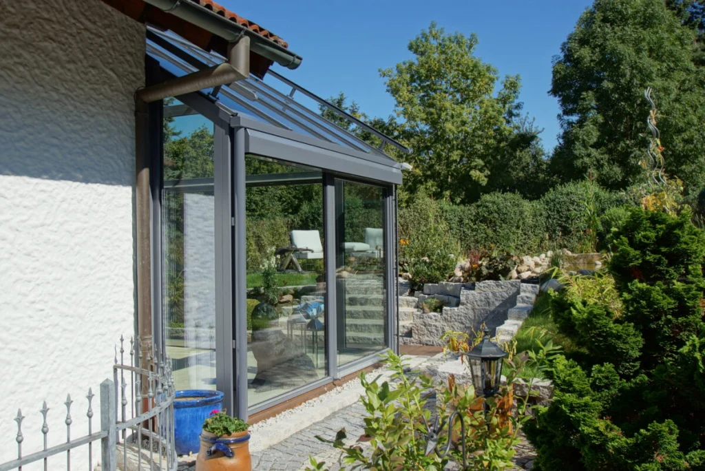 Wintergarten in Bayreuth, Seitenansicht mit Pultdach, anthrazitfarbenen Profilen und Schiebetür zum Hanggarten