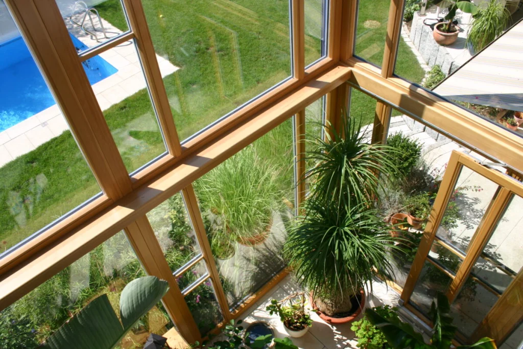 Blick aus dem Obergeschoss des Wintergartens in Bubenreuth durch die Holzrahmen hinunter auf Garten und Pool