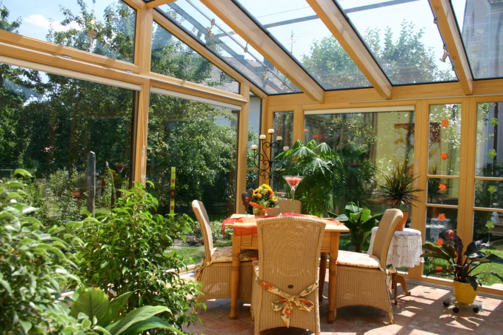 Wintergarten in Dechsendorf von innen mit Glasdach, Fensterfront aus Holz und Esstisch mit Rattanstühlen