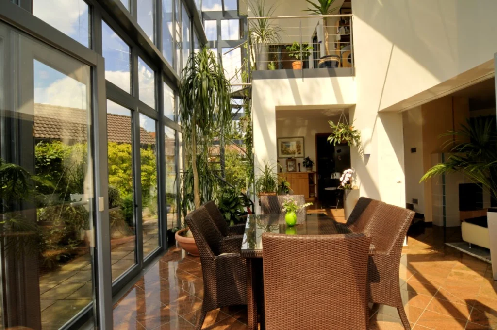 Essplatz im Glasvorbau in Fürth mit Rattanstühlen vor der Glasfassade, Galerie und Wendeltreppe
