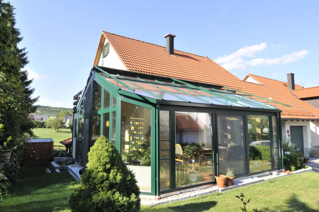 Pultdach-Wintergarten in Großenbuch mit dunkelgrünen Rahmen und Glasdach an einem Haus mit rotem Ziegeldach