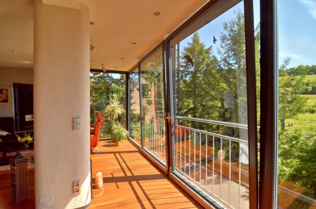 Anbau in Marktsteinach von innen, raumhohe Verglasung mit Blick auf Balkon, Wiesen und Wald