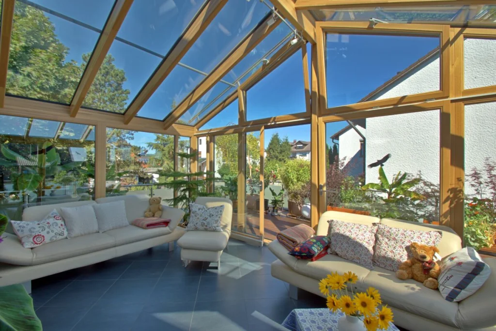 Wintergarten in Neudrossenfeld von innen, Holzsparren mit Glasdach, gekipptes Fenster, Ledersofas und Sonnenblumen