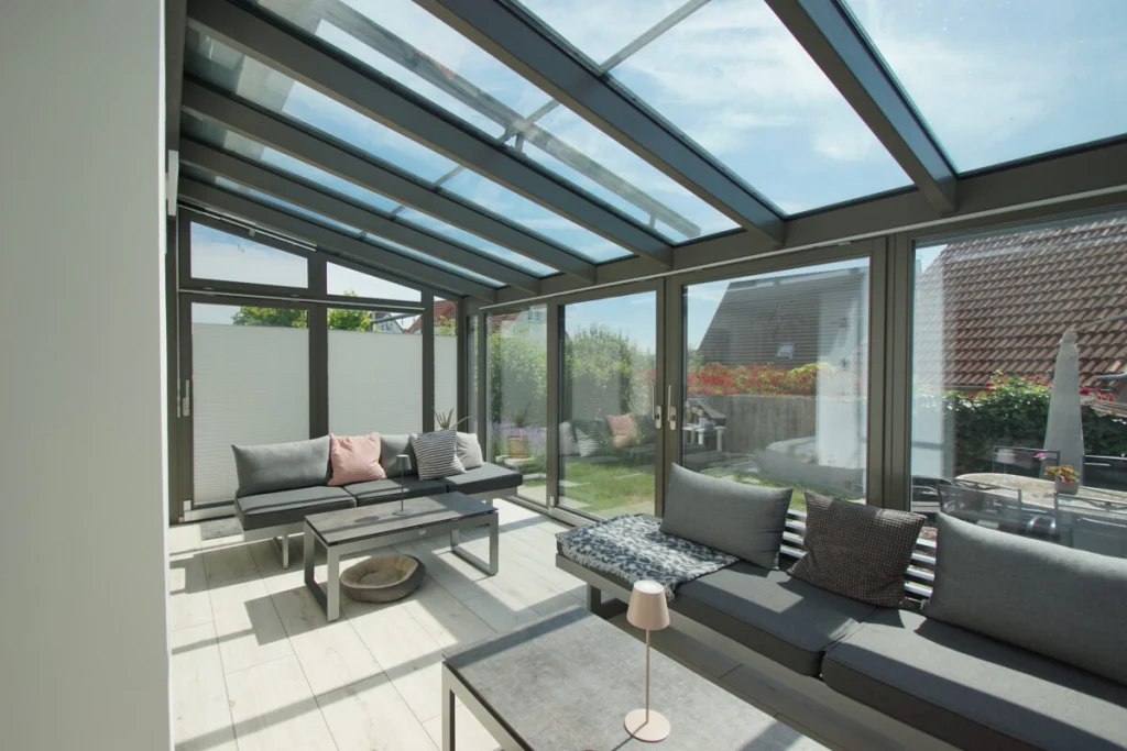 Wintergarten in Baunach mit Pultdach aus Glas, grauen Profilen und Loungemöbeln, Innenansicht