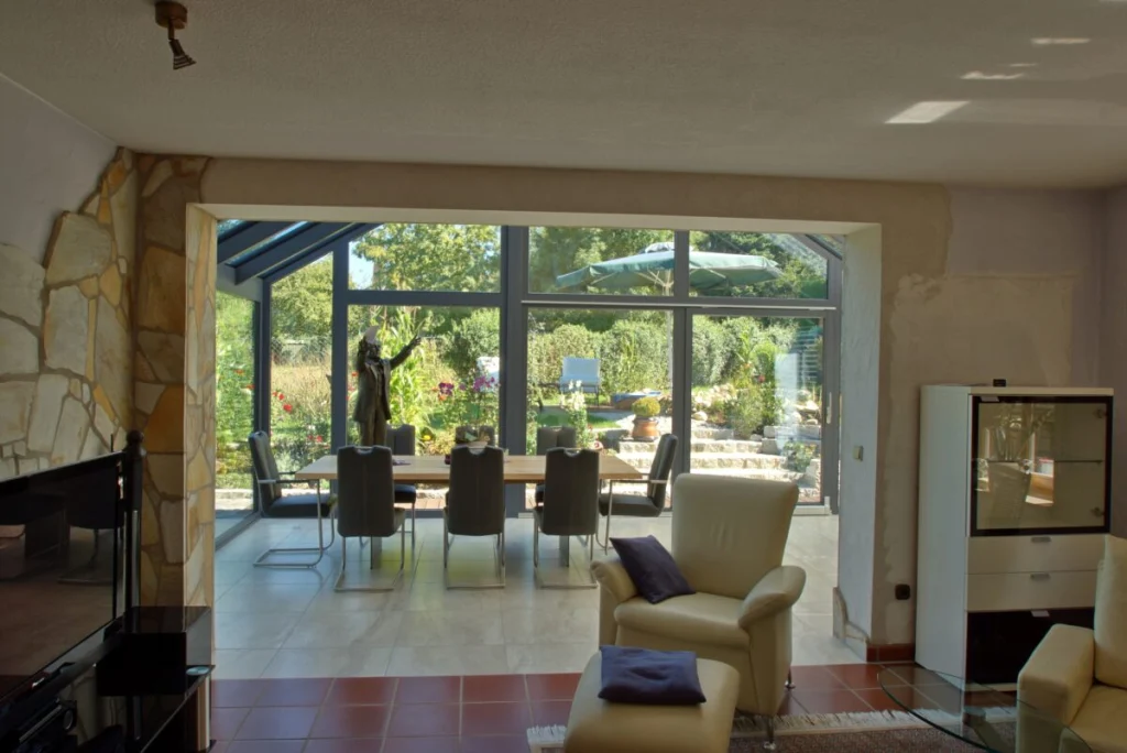 Wintergarten in Bayreuth vom Wohnzimmer aus, Esstisch mit Freischwingern vor der Glasfassade zum Garten