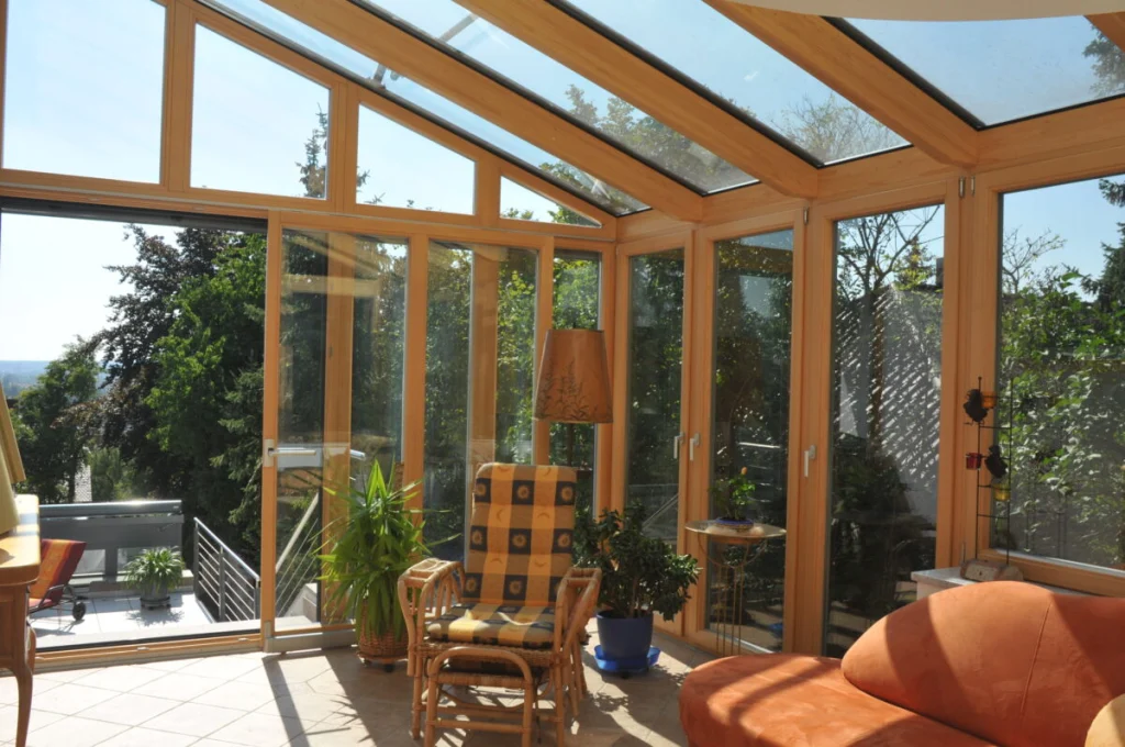 Wohnwintergarten in Buckenhofen mit verglastem Giebel, Holzrahmen natur, Tür zur Terrasse und Blick über Bäume