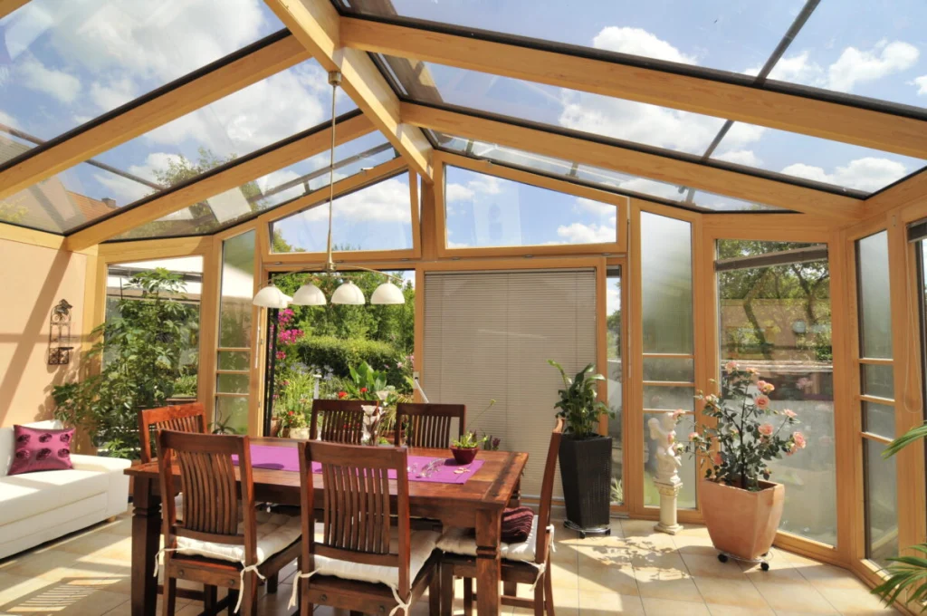 Wintergarten in Burk von innen mit Glasdach, hellen Holzrahmen, Esstisch und gedämmter Rückwand