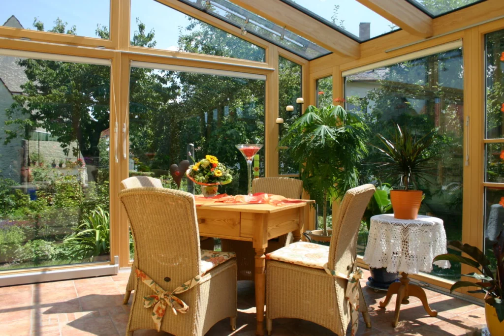 Sitzecke im Wintergarten in Dechsendorf mit zweiflügeliger Holztür, Rattanstühlen und Gartenblick