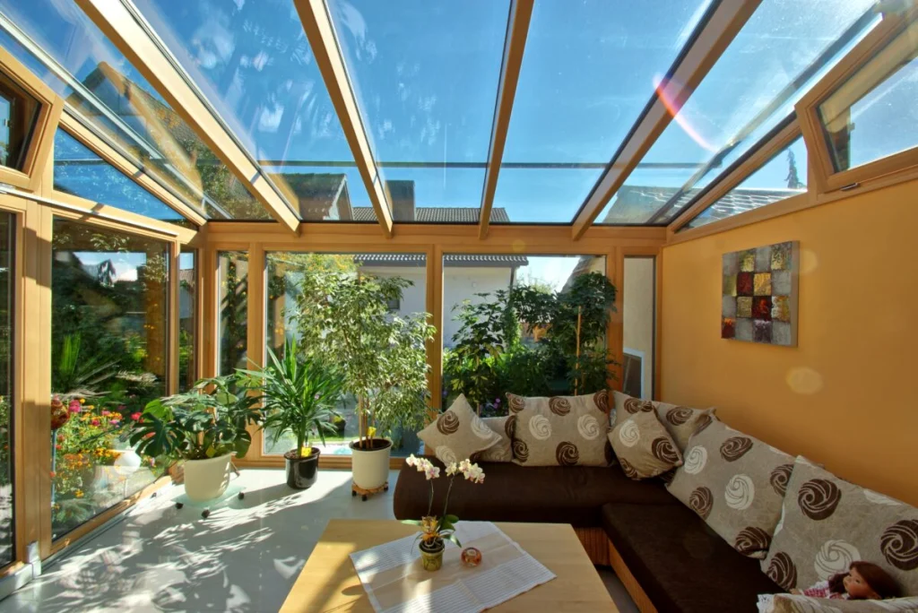 Wintergarten in Ebensfeld innen mit Glasdach unter blauem Himmel, Kippfenstern und Eckcouch