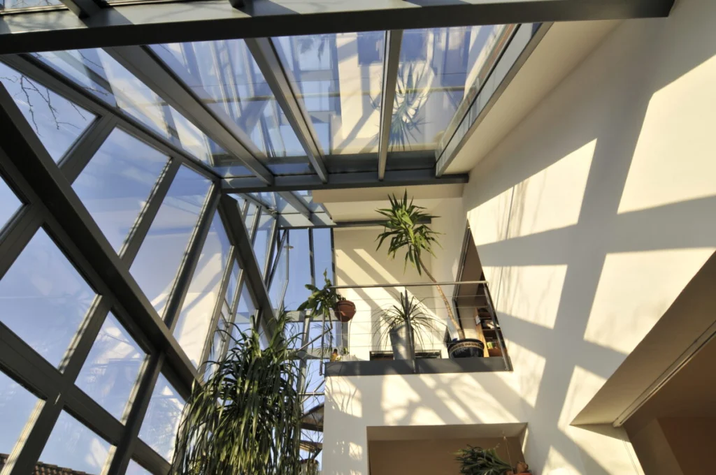 Glasdach und Glasfassade des dreigeschossigen Vorbaus in Fürth von unten mit Galerie und Pflanzen