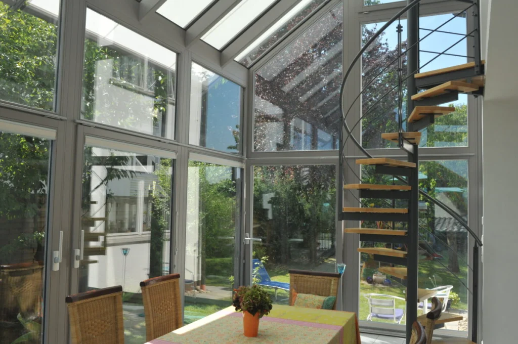 Wintergarten in Leutenbach von innen, graue Profile, Wendeltreppe, Esstisch und Blick auf den Garten
