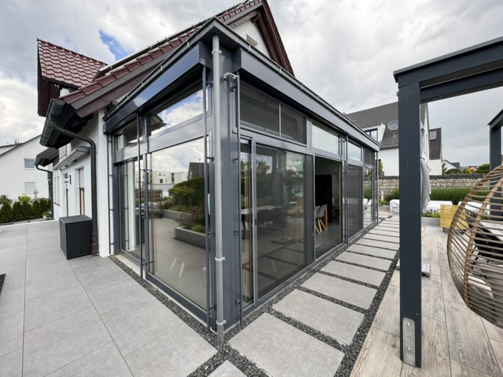 Anbau in Benzendorf mit Flachdach und anthrazitfarbenen Rahmen von der Terrasse mit Pergola gesehen