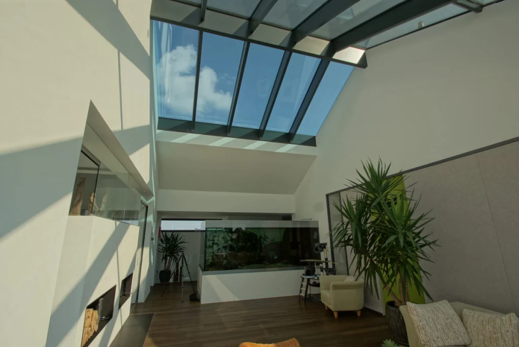 Wohnraum in Buckenreuth mit Glasdach im Satteldach, Aquarium, Palmen und Ledersessel