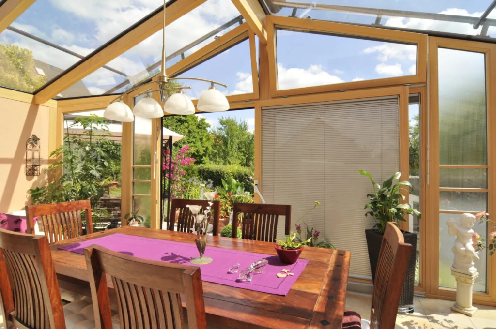Esstisch im Wintergarten in Burk unter dem Glasdach, Blick durch die offene Tür in den Garten