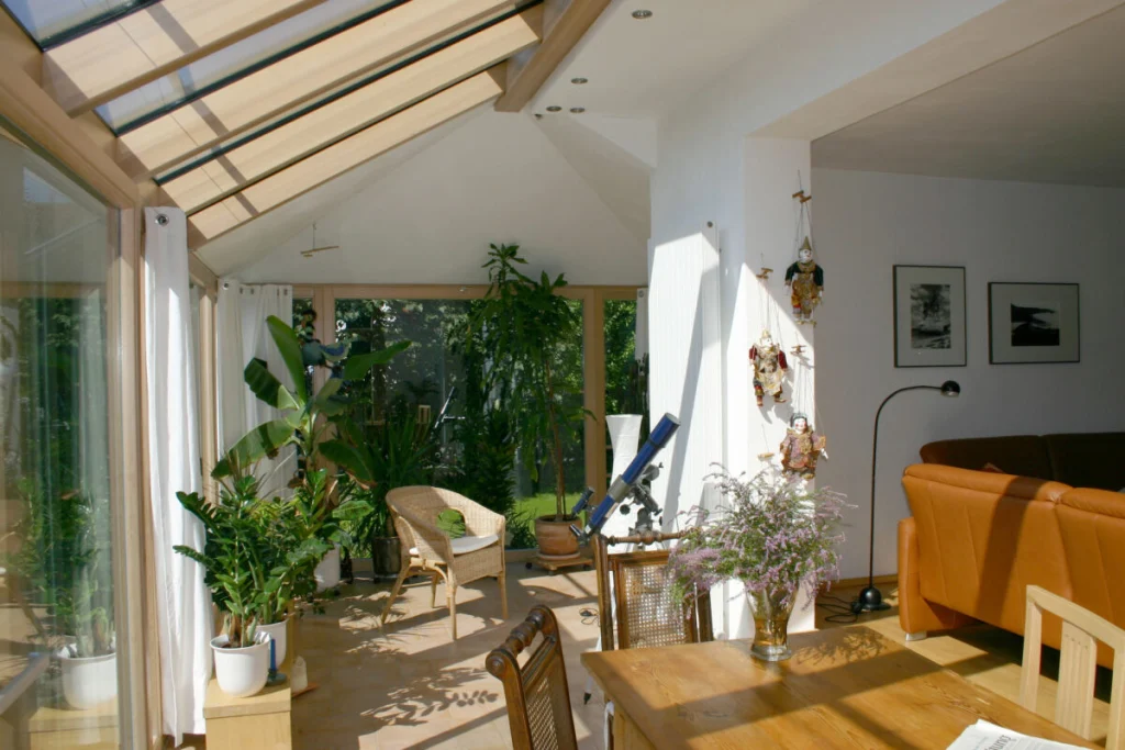 Blick aus dem Wohnzimmer in den Wintergarten in Großenseebach mit Glasdach, gedämmter Decke und Pflanzen