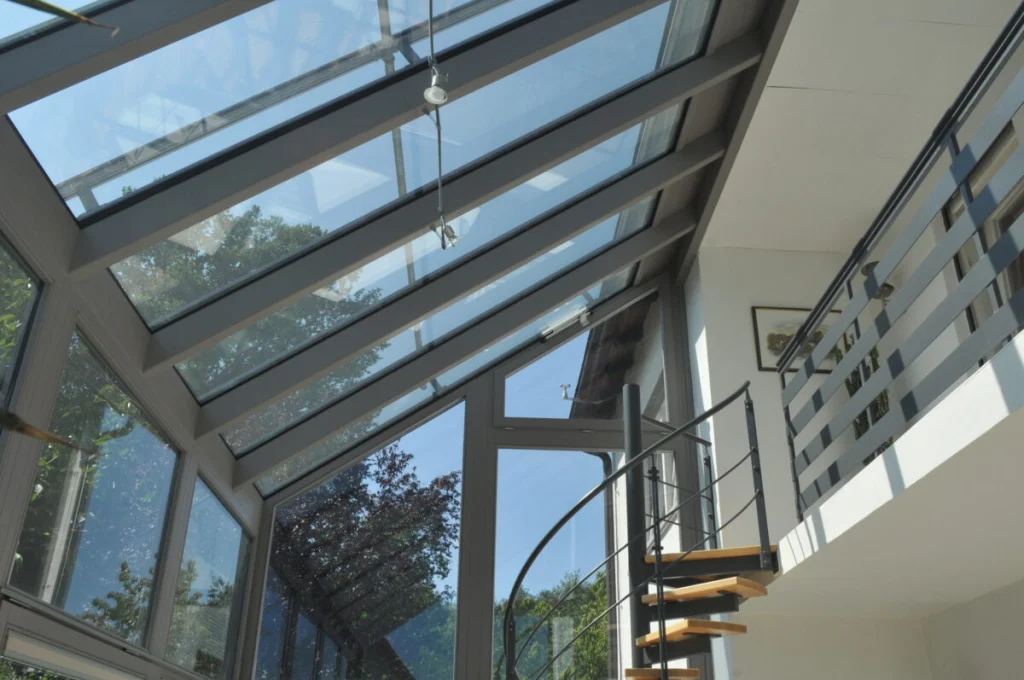 Glasdach des Wintergartens in Leutenbach von unten, graue Sparren, Seilleuchten und Wendeltreppe