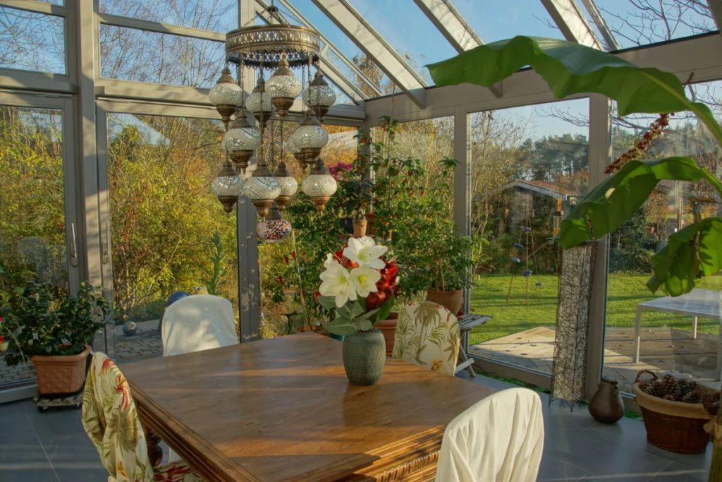 Wintergarten in Möhrendorf von innen, Holztisch mit Amaryllis, Mosaikleuchte, Bananenstaude und Blick in den Garten