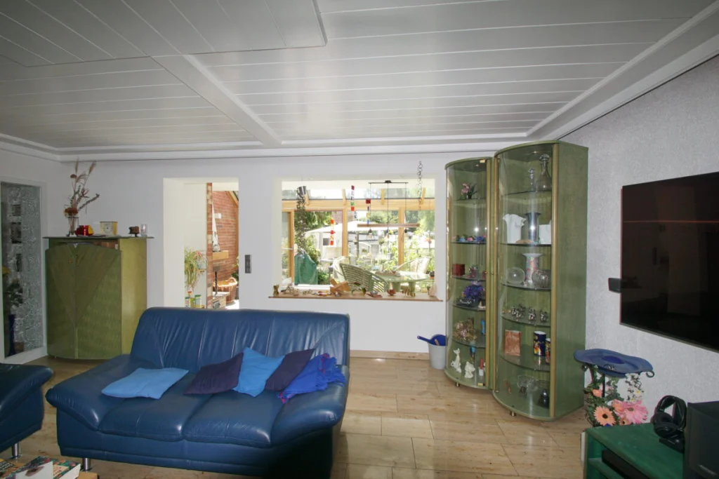 Blick aus dem Wohnzimmer durch ein Fenster in den Wintergarten in Ahorntal mit Holzkonstruktion
