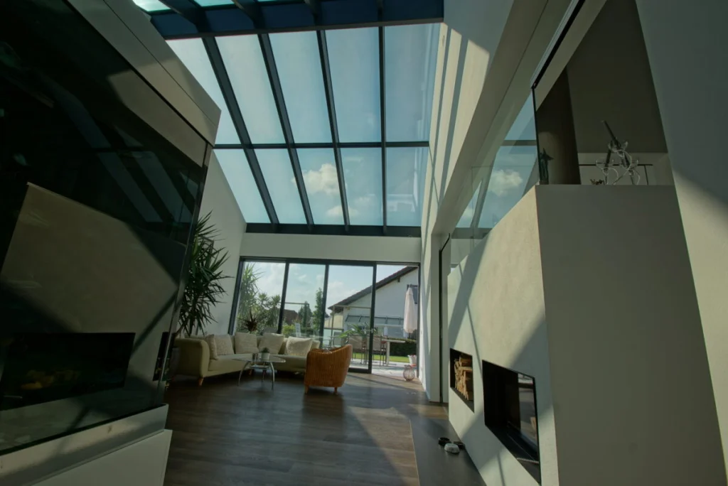 Glassatteldach in Buckenreuth von innen, Blick über das Aquarium zur Schiebetür mit Sofa und Terrasse