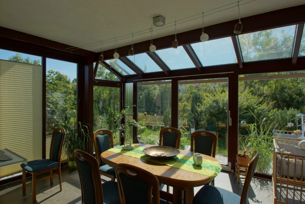 Wintergarten in Heiligenstadt von innen mit dunklen Profilen, Glasdach, Esstisch und Blick in den Garten