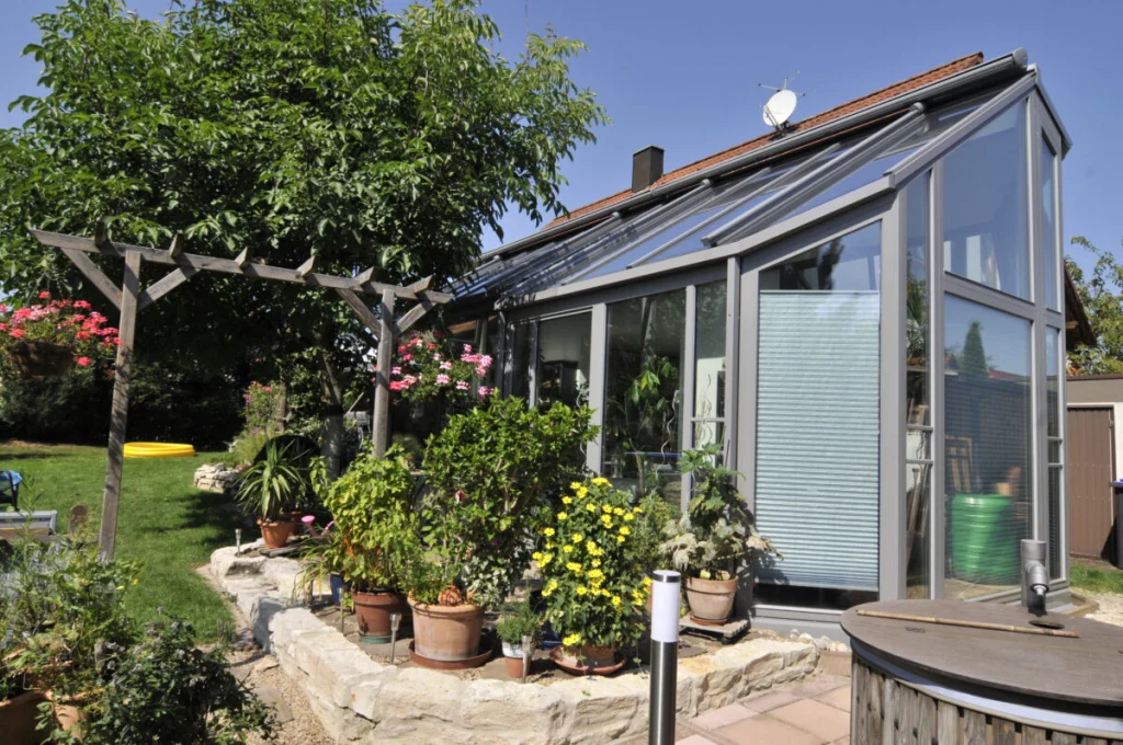 Wintergarten in Kleinsendelbach mit Pultdach, grauen Profilen, Plissees und geschlossenem Dachteil am Haus