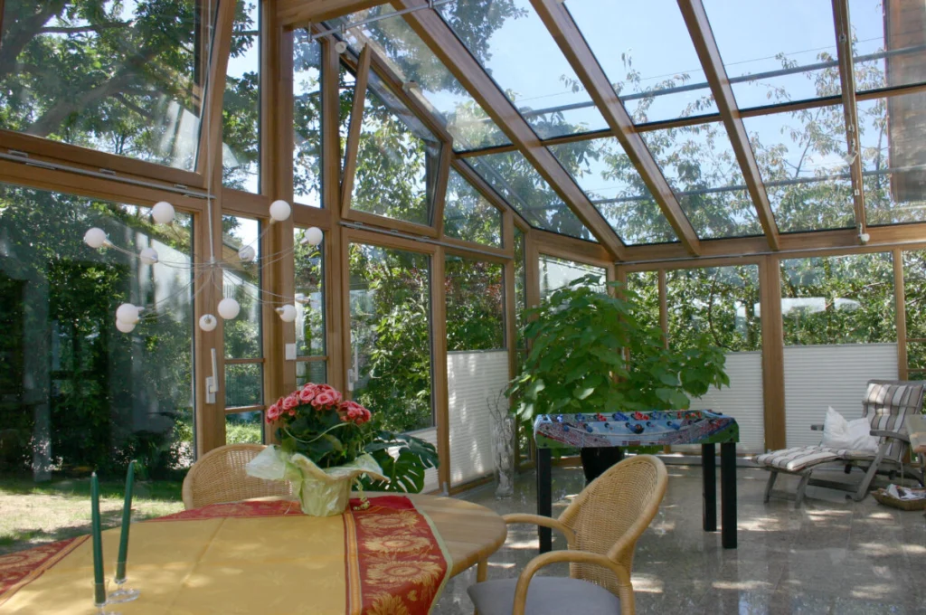 Wintergarten in Kunreuth von innen mit Holzsparren und Glasgiebel, gekipptes Fenster, Pflanzen und Liege
