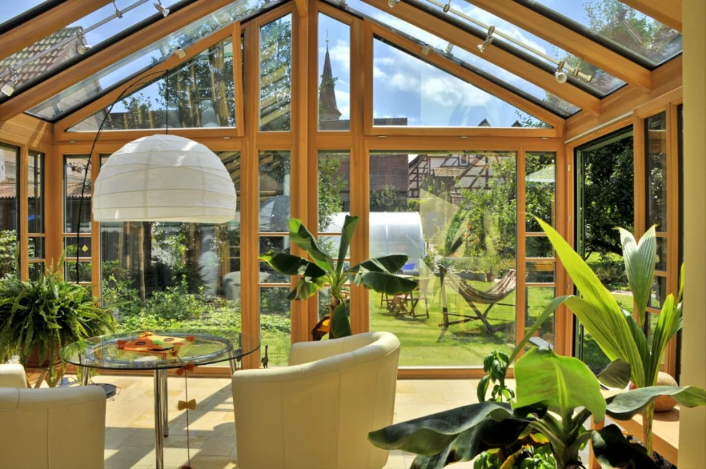 Wintergarten in Lauf von innen mit Glasgiebel aus Holz, Blick auf Garten mit Hängematte, Gewächshaus und Kirchturm