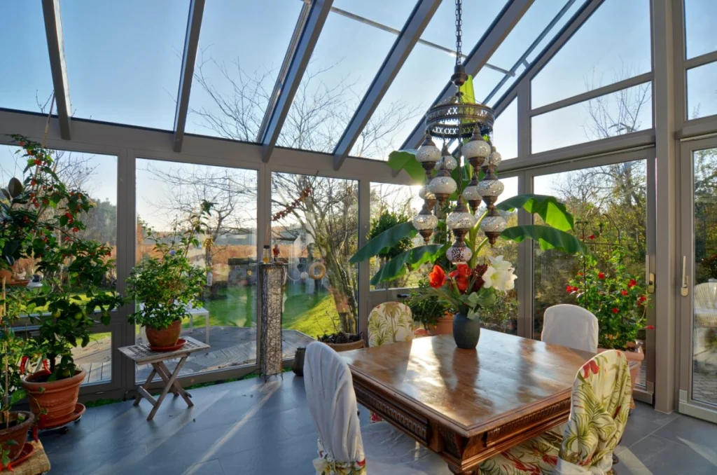 Wintergarten in Möhrendorf von innen, Glasdach mit Firstlüftung, Esstisch, Mosaikleuchte und Blick in den Garten