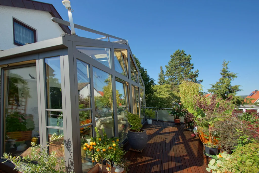 Wintergarten in Neudrossenfeld auf der Dachterrasse, anthrazitfarbene Profile, Holzdeck mit Kübelpflanzen