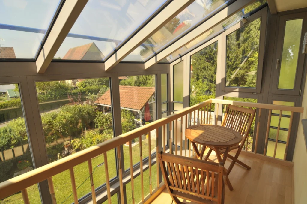 Wintergarten in Hannberg, Galerie im Obergeschoss mit Holzgeländer, Klapptisch und Stühlen unter dem Glasdach