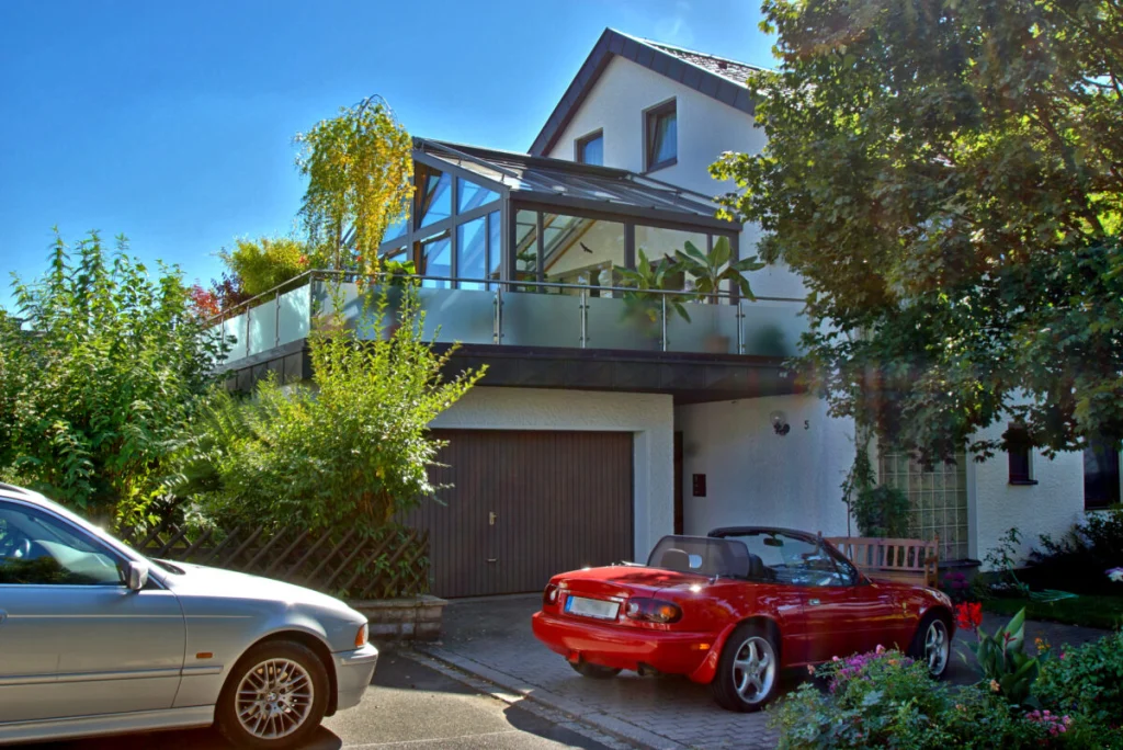 Wohnhaus in Neudrossenfeld mit Satteldach-Wintergarten auf der Doppelgarage, Balkon mit Milchglasbrüstung, Einfahrt