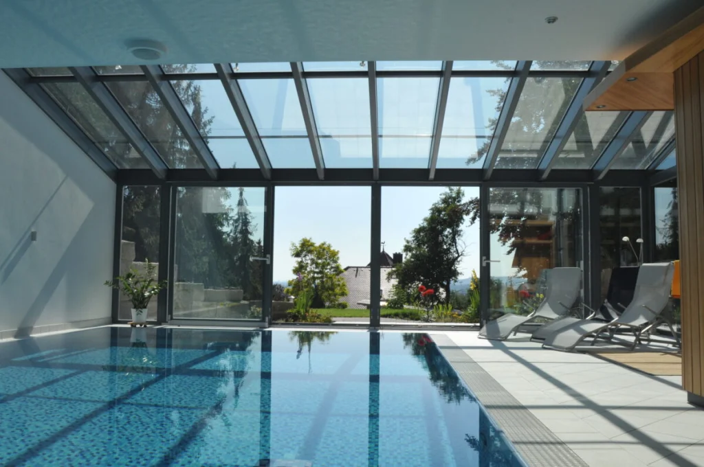 Schwimmbad-Wintergarten in Buckenhofen mit Glasdach, anthrazitfarbenen Rahmen und Blick über den Garten