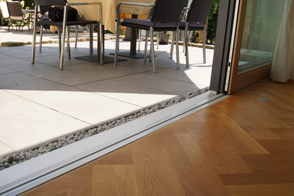 Laufschiene der Schiebetür im Anbau in Coburg, bodenbündig zwischen Parkett und Terrassenplatten