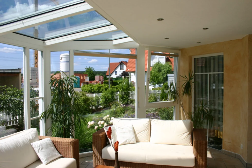 Wintergarten in Hausen von innen mit weißem Glasdach, gekipptem Fenster und Blick in den Garten