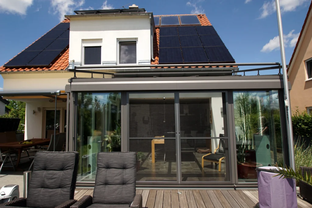 Wintergarten in Königsfeld von der Terrasse aus, Anbau mit Flachdach, dunklen Profilen und Schiebetüren mit Insektenschutz