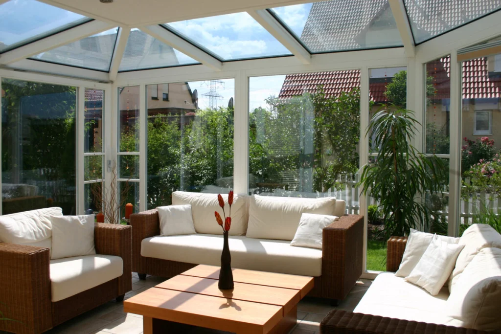 Wohnwintergarten in Hausen von innen, weißes Glasdach, Rattanmöbel und Blick auf die Nachbarschaft