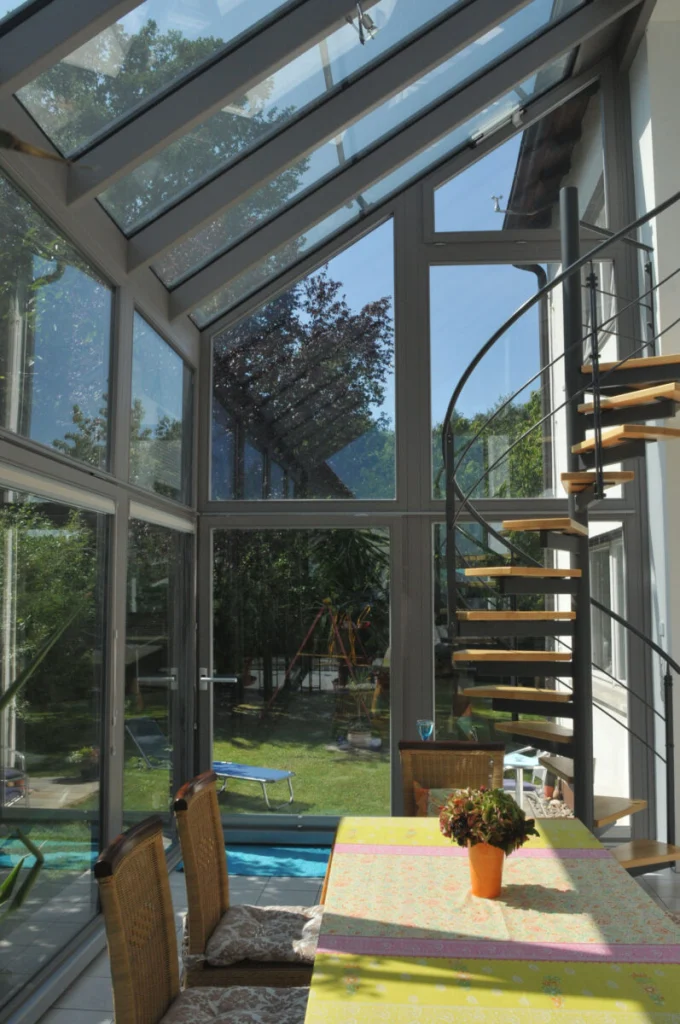 Wintergarten in Leutenbach mit Wendeltreppe, graue Profile, Glasdach und Blick auf Garten mit Spielplatz