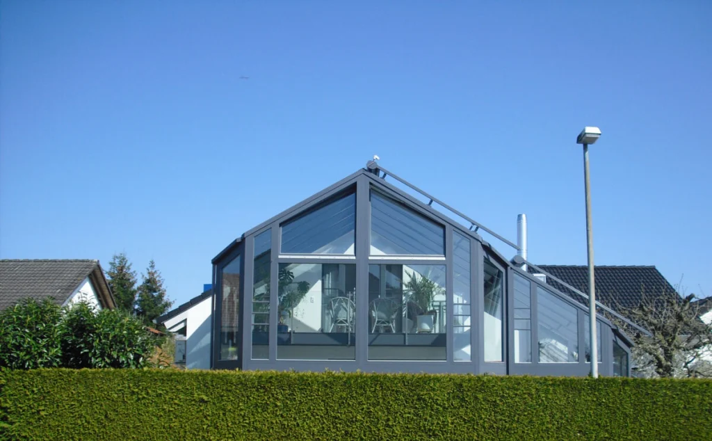 Wintergarten in Baiersdorf von außen, zweigeschossiger Glasgiebel mit Satteldach und dunkelgrauer Konstruktion