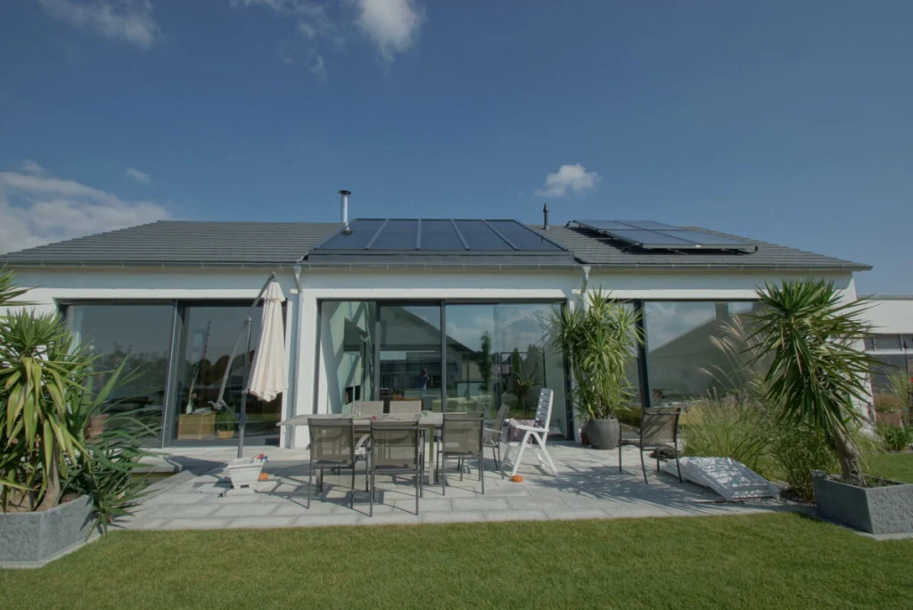 Bungalow in Buckenreuth mit Glasdach im Satteldach, große Schiebefenster, Terrasse mit Esstisch und Palmen