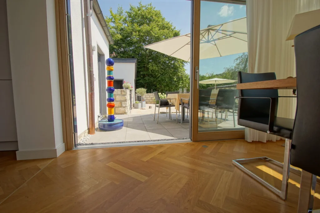 Schwellenloser Übergang vom Parkett des Anbaus in Coburg auf die Terrasse durch die offene Schiebetür
