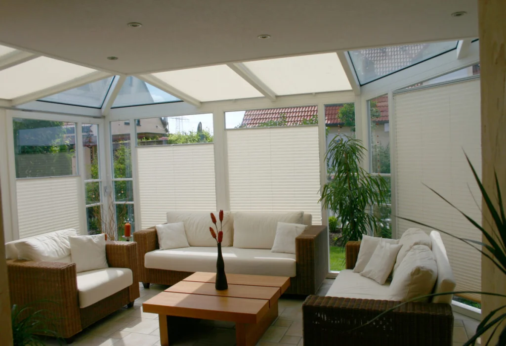 Wintergarten in Hausen von innen mit heruntergelassenen Plissees und Dachbeschattung, Rattansofas