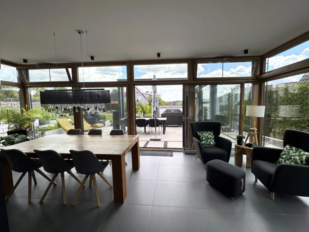 Ess- und Wohnbereich im Anbau in Benzendorf mit Eichentisch, Sesseln und Schiebetür zur Terrasse